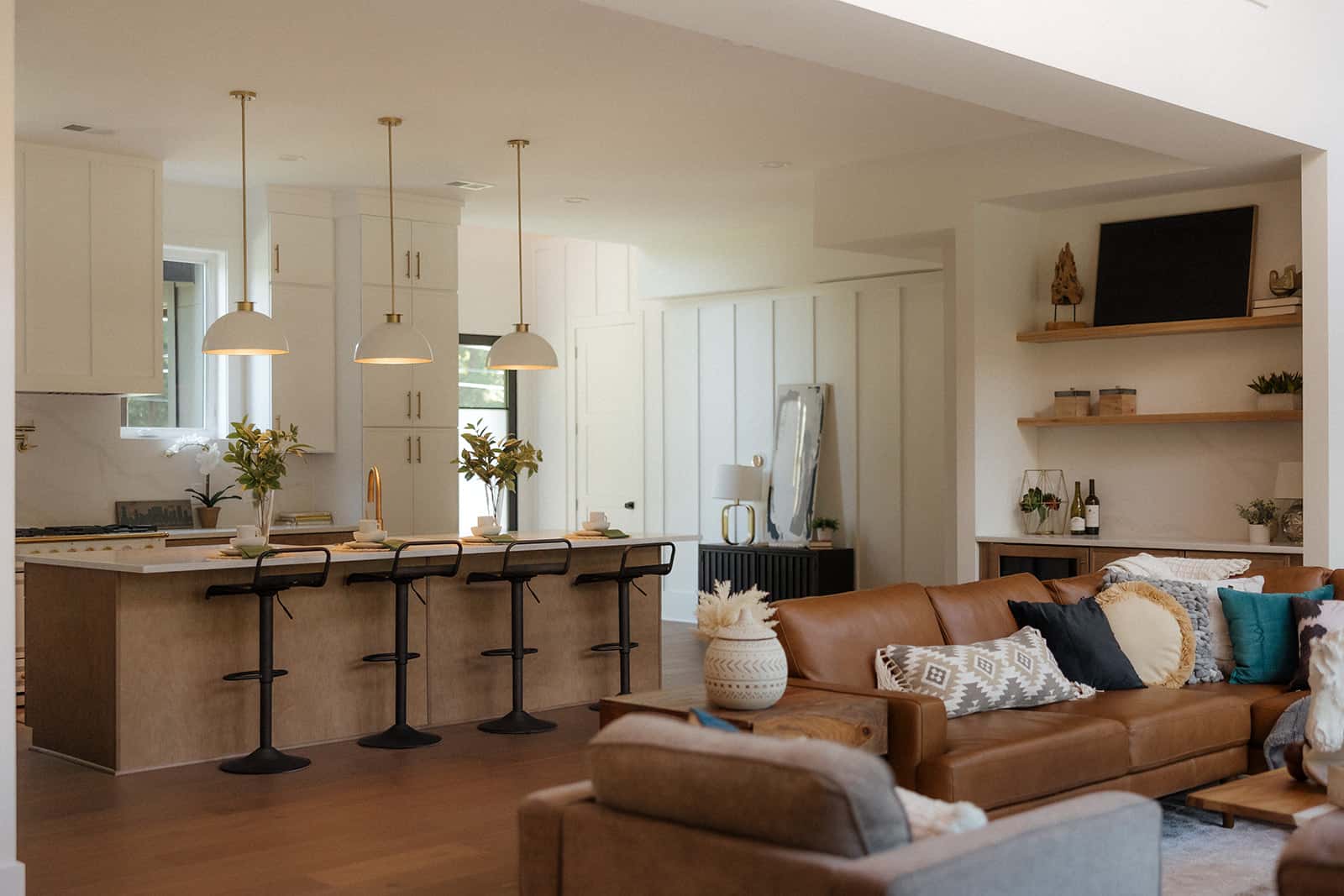 Open-concept kitchen and living room with white cabinetry and leather sectional