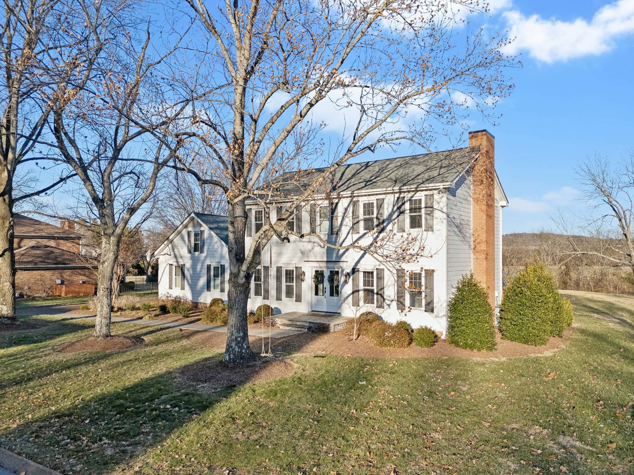 Sold: white colonial with black shutters and a brick chimney on a sloping Brentwood lawn