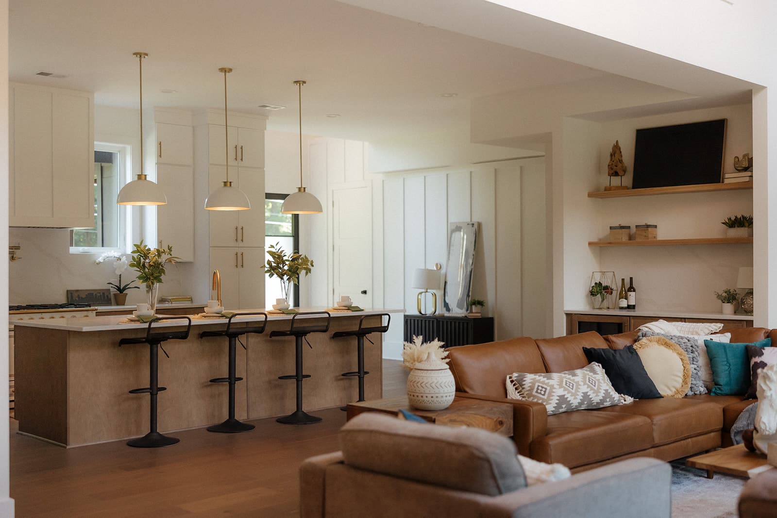Open-concept kitchen and living room with white cabinetry and leather sectional