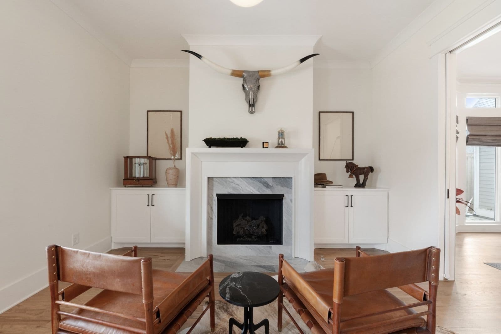 Styled sitting room with marble fireplace, leather chairs, and longhorn mount from a Ryan Boggs listing